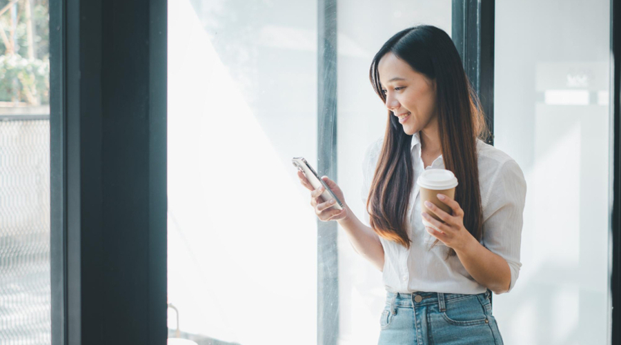 Professional woman checking her social media with a coffee cup in hand