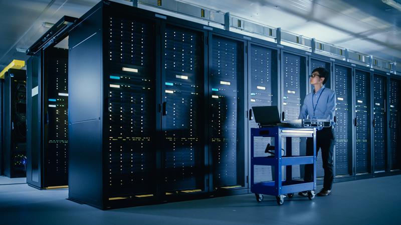Humans Become Indispensable as IT Innovations Accelerate IT worker standing in a database center