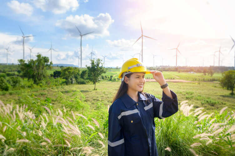 A Female Engineer for a Green Job Project is posing in a Farm of Wind Turbines