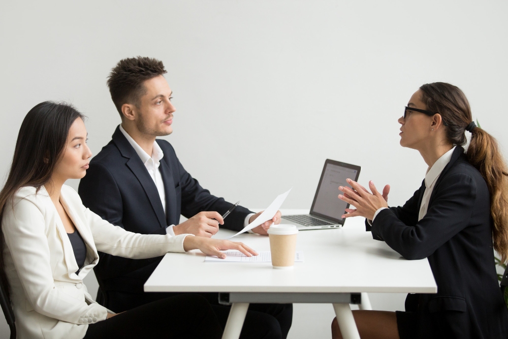 female applicant interviewed by hr manager and recruiter with tough questions face to face office setting