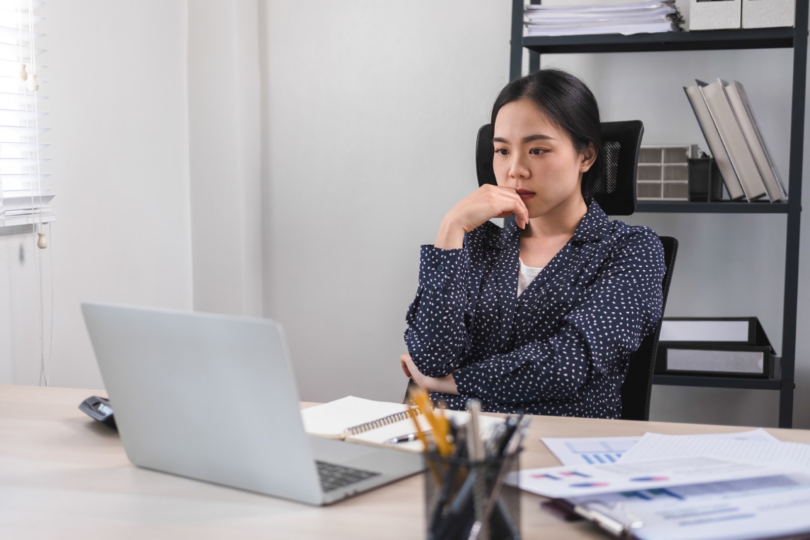 Female office worker thinking and worrying about her career in an office setting