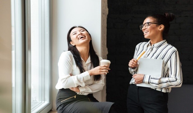 Hai nhân viên văn phòng đang cởi mở vui vẻ chia sẻ câu chuyện với nhau