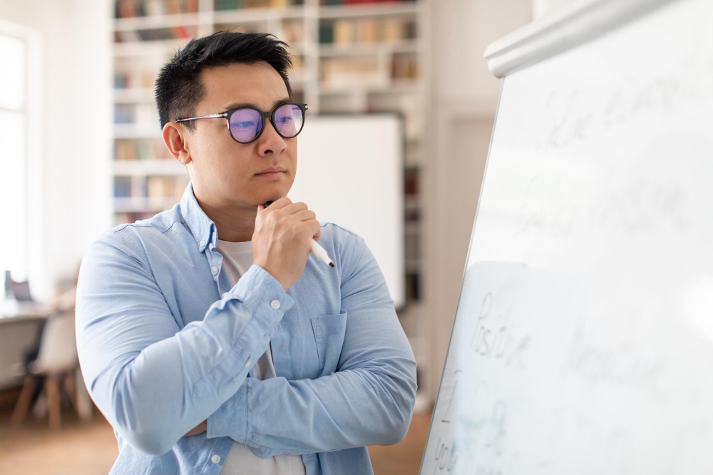 Middle-aged office worker focusing on solving a problem while writing on a white board