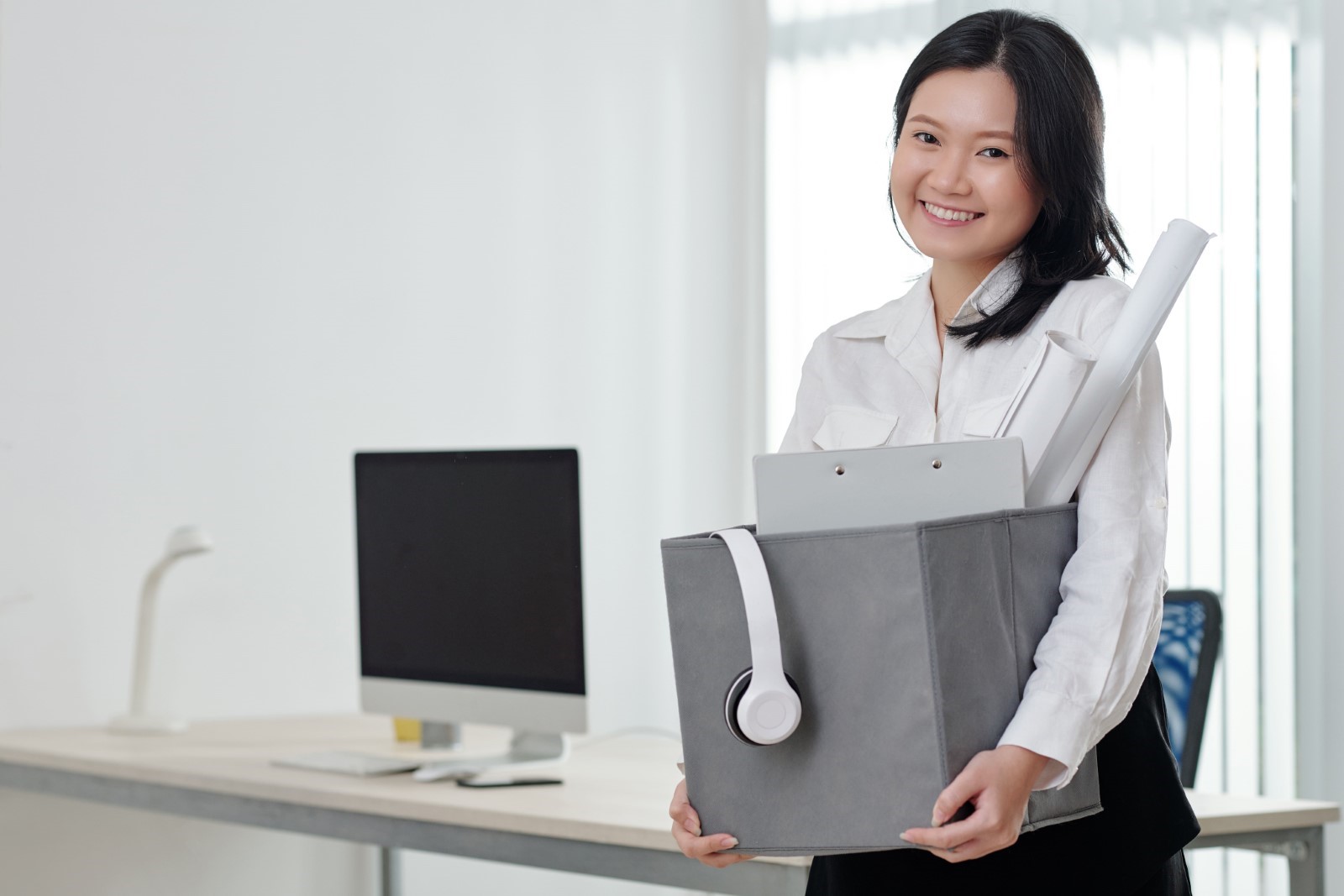 Female office worker packing up her things to leave the company with a smile on her face