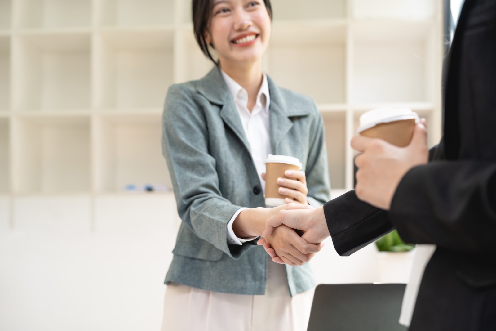 Hai đồng nghiệp bắt tay nhau và cười vui vẻ tại văn phòng