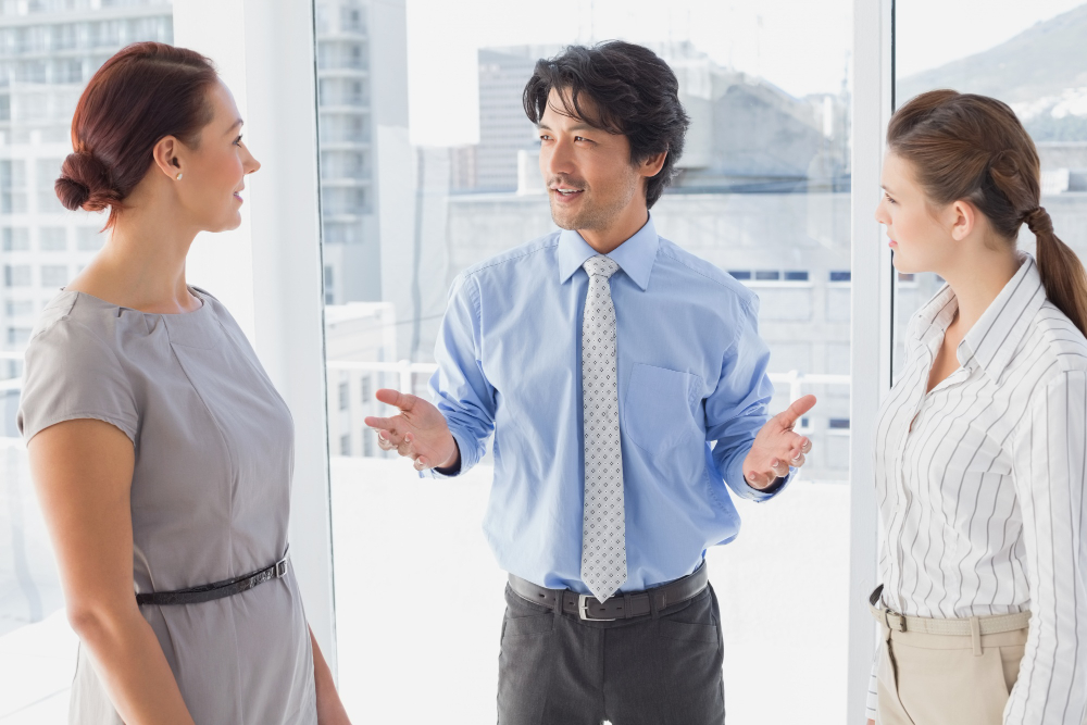 A coachable businessman discussing work with co-workers at ManpowerGroup Vietnam office  