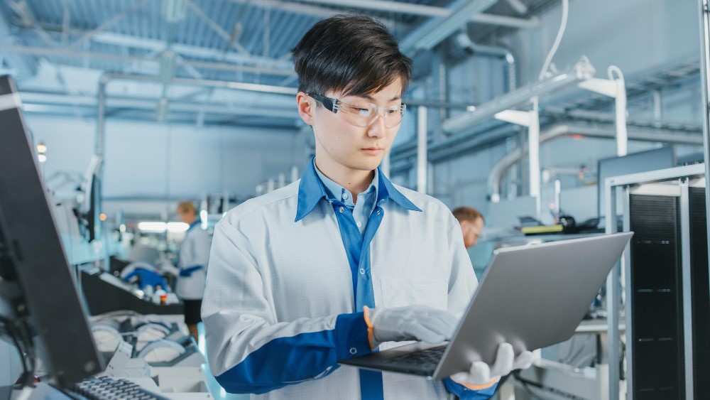 A technician in a laboratory setting working on a laptop