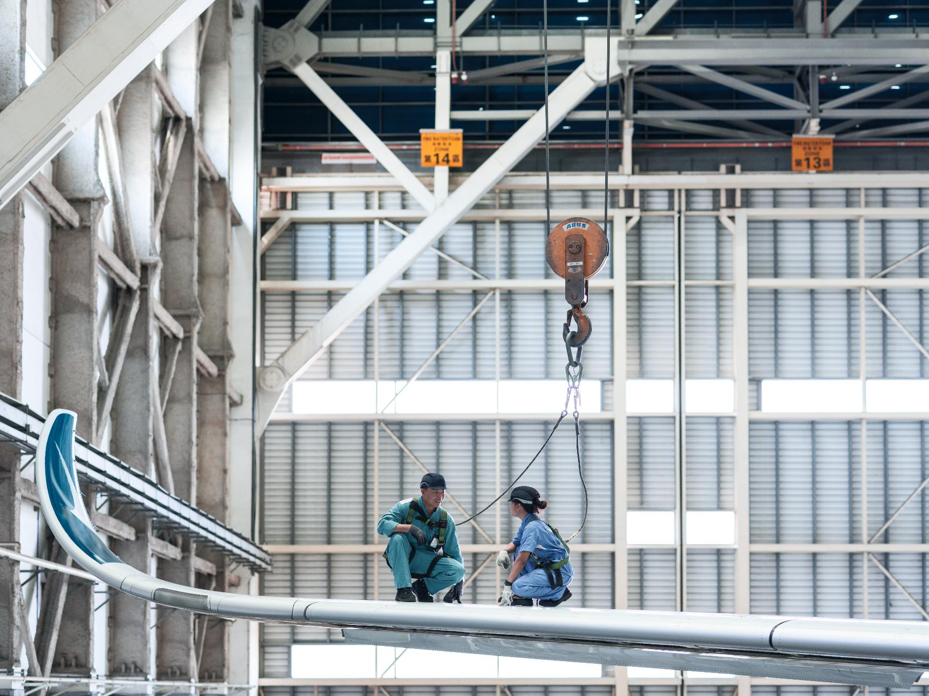 Two Aircraft Engineering Licence Trainees standing on the airplane during work at a HAECO hangar