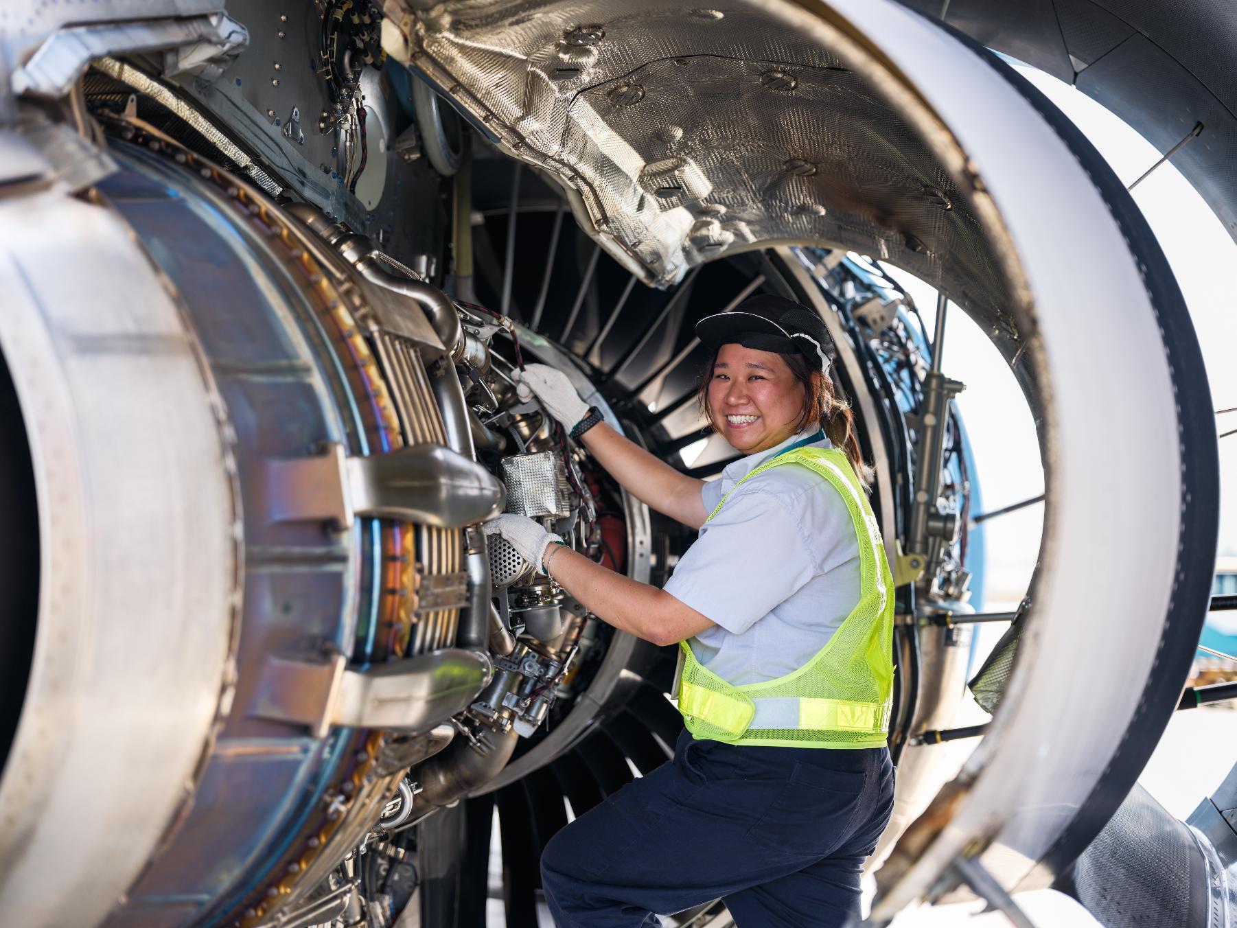 A female Aircraft Engineering Licence Trainee checking an airplane's components at a HAECO Group hangar