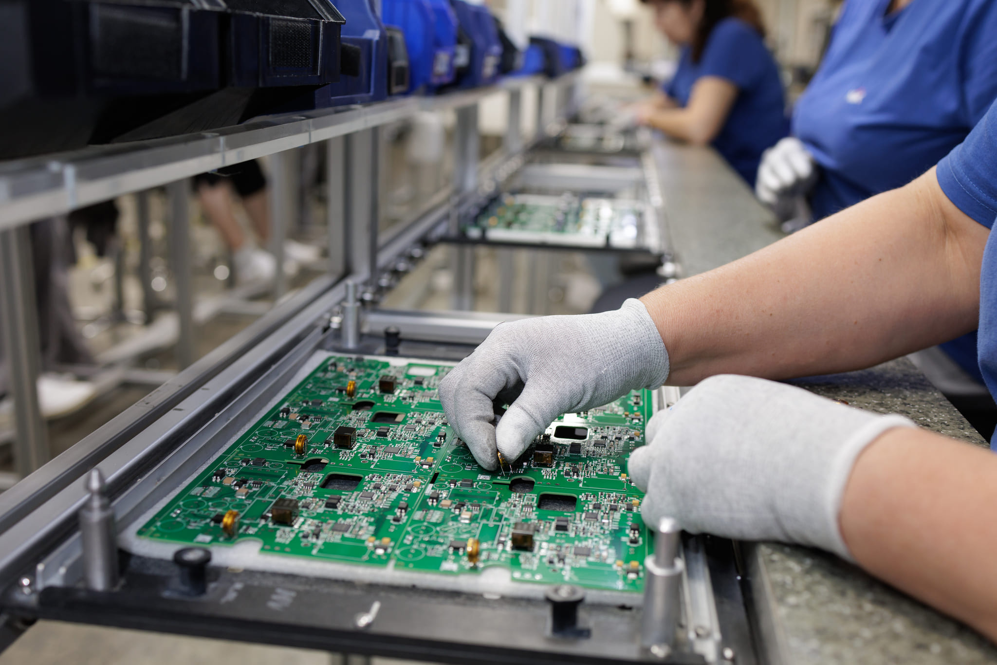 Precision manufacturing technician inspecting electronic components on an assembly line