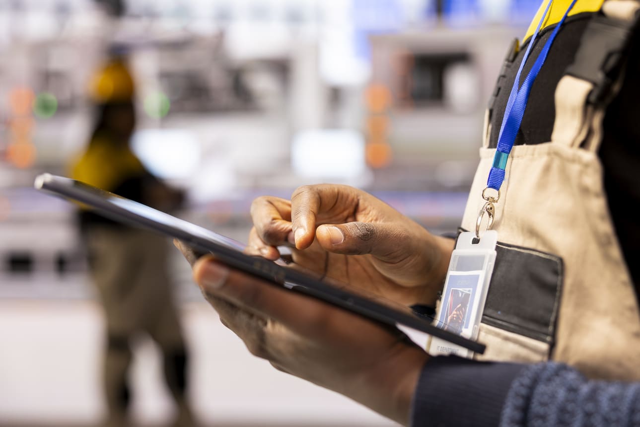 Shift supervisor checking attendance records near an active assembly line