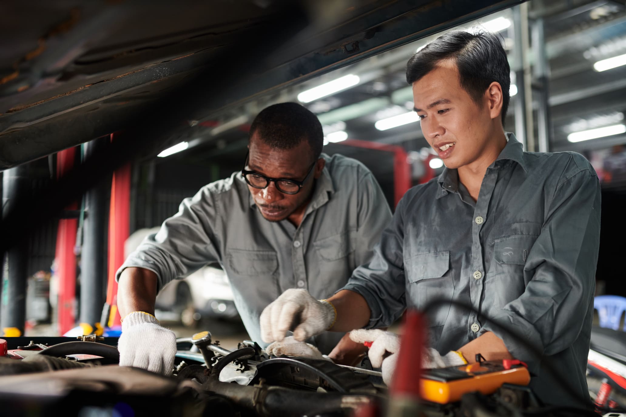 Kỹ thuật viên ô tô cao cấp hướng dẫn nhân viên trẻ bảo trì thiết bị
