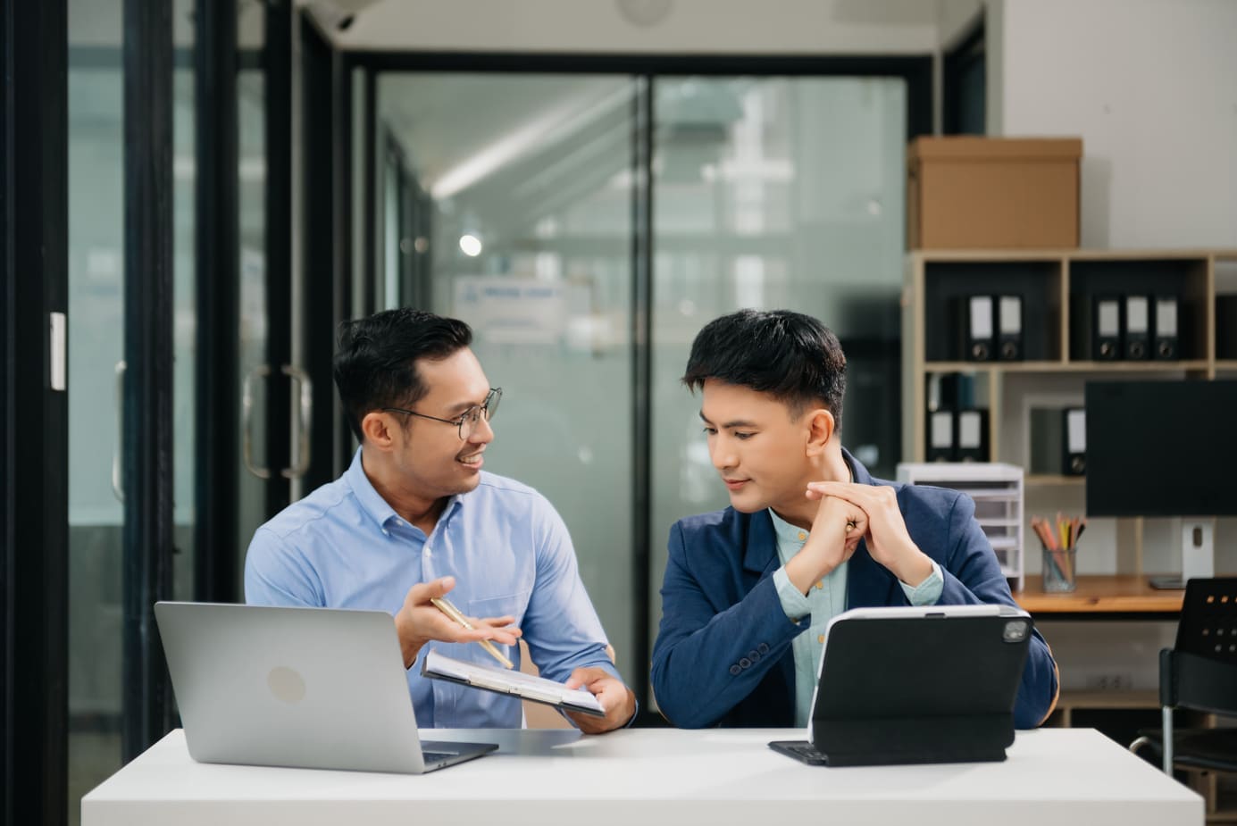 Foreign project specialist reviewing project deliverables with a local colleague in a modern workplace