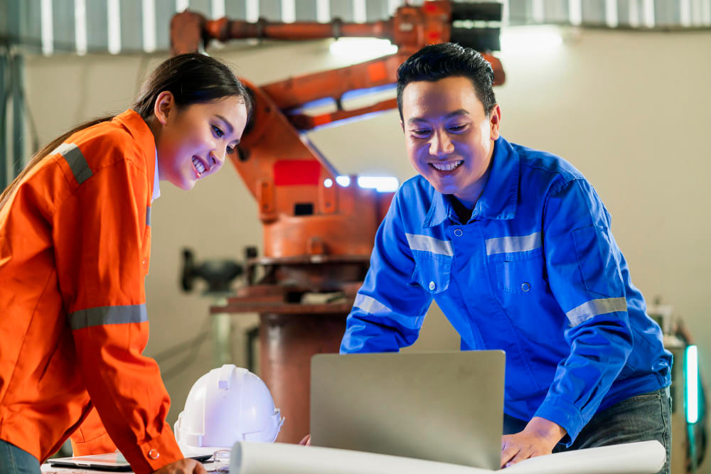 Experienced factory supervisor training a new operator on standard assembly procedures