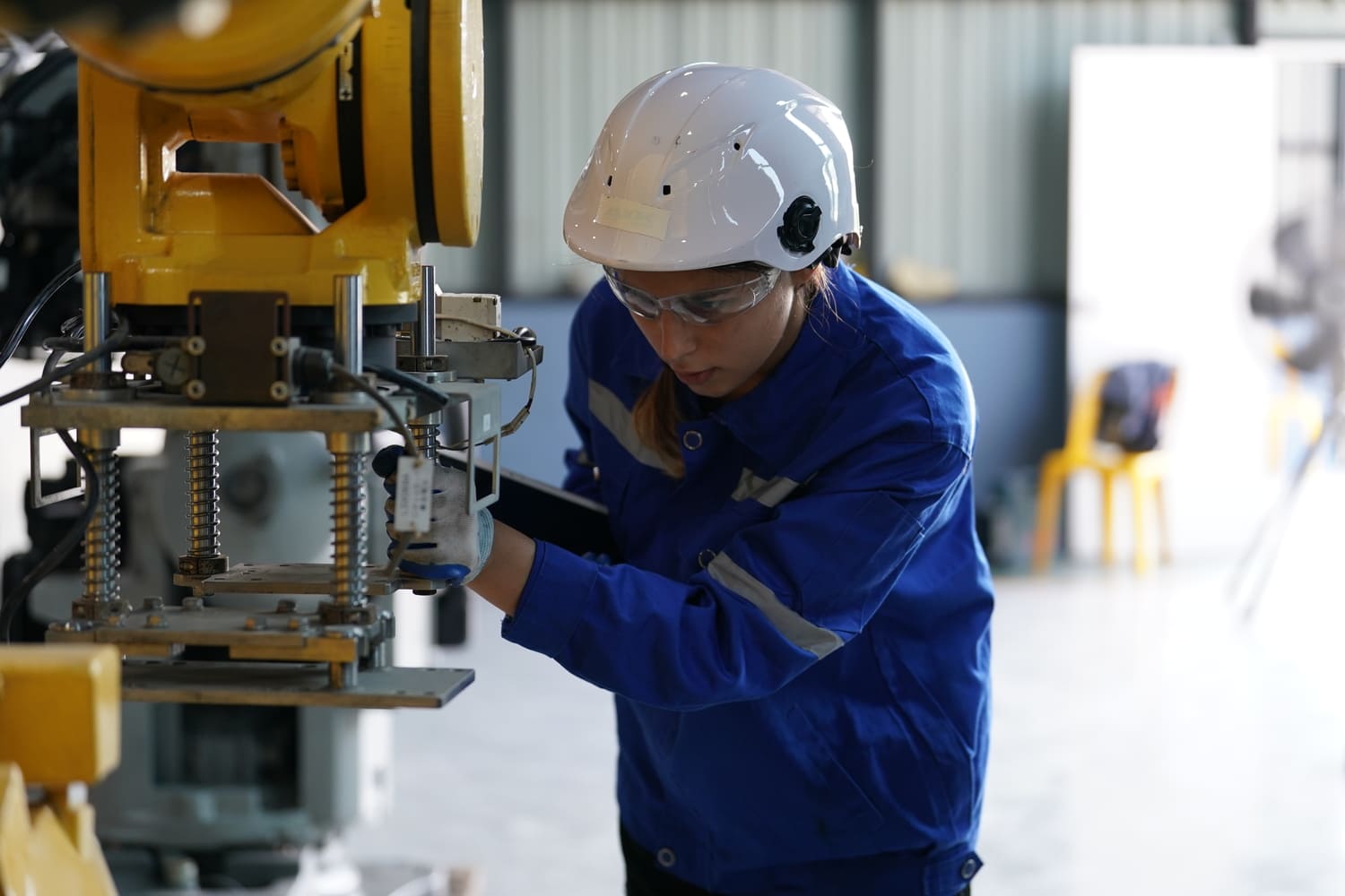 Skilled technical employee operating precision machinery on a manufacturing assembly line.