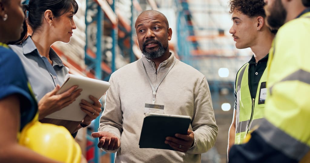 Shift manager gathering a cohort of line operators near an assembly line