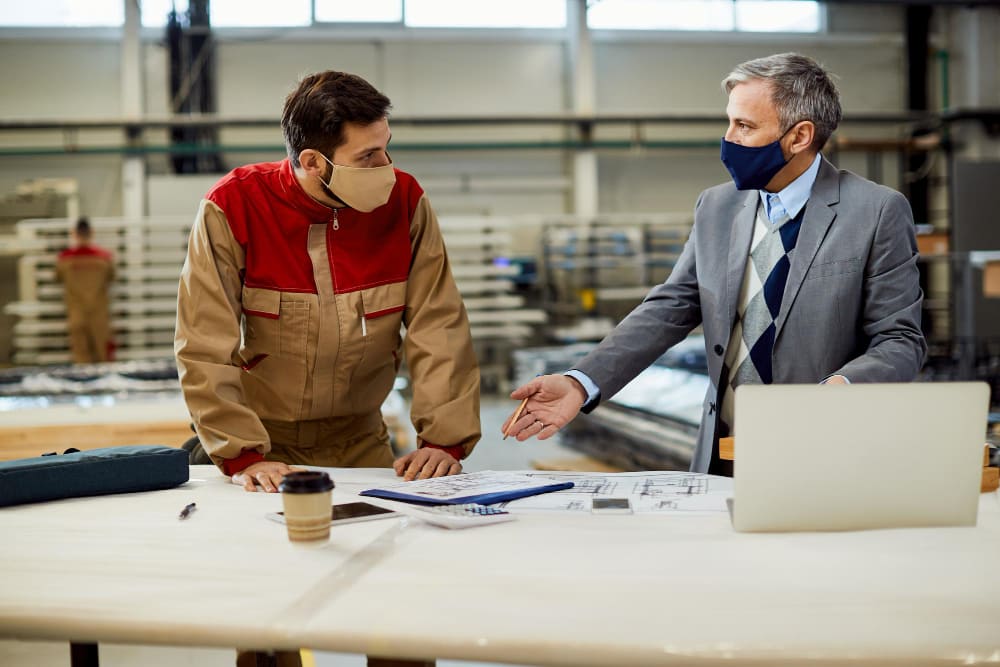 Factory compliance officer and HR manager reviewing temporary employee contracts and audit documentation