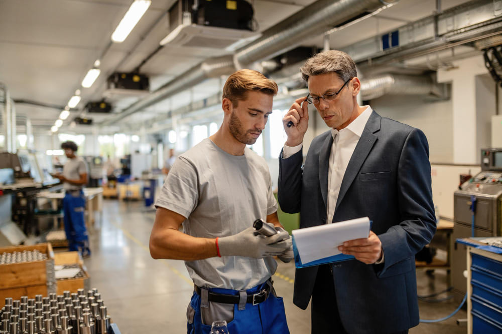 Senior technician guiding a temporary worker on standardized equipment assembly on the shop floor