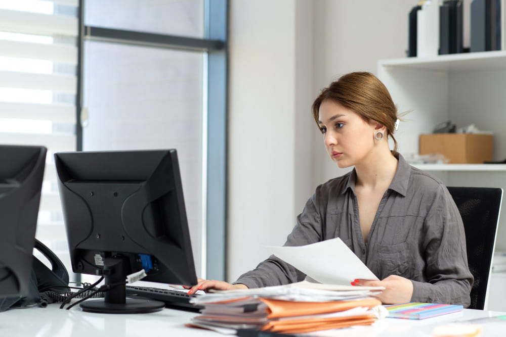 HR manager reviewing expatriate work permit applications and employee documentation at an office desk