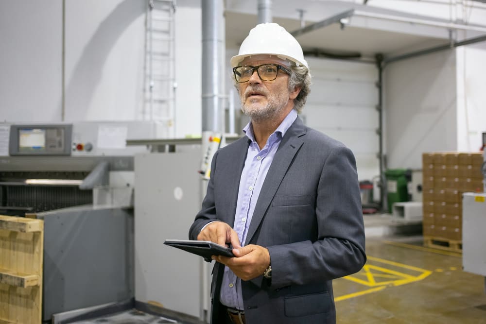 Operations specialist inspecting facility workflow with a digital tablet in a manufacturing plant