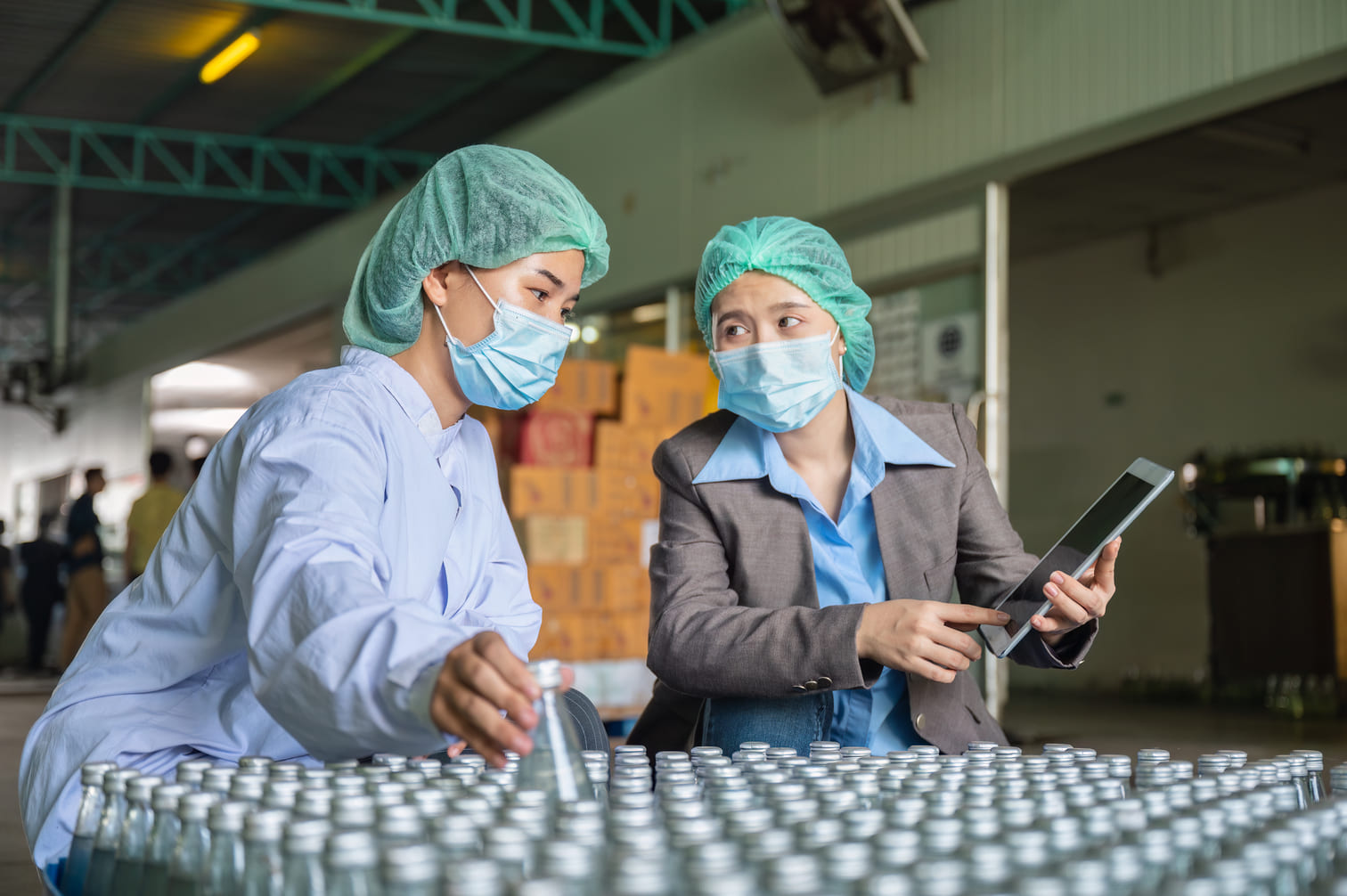 Factory plant manager and technician inspecting production line operations with a tablet
