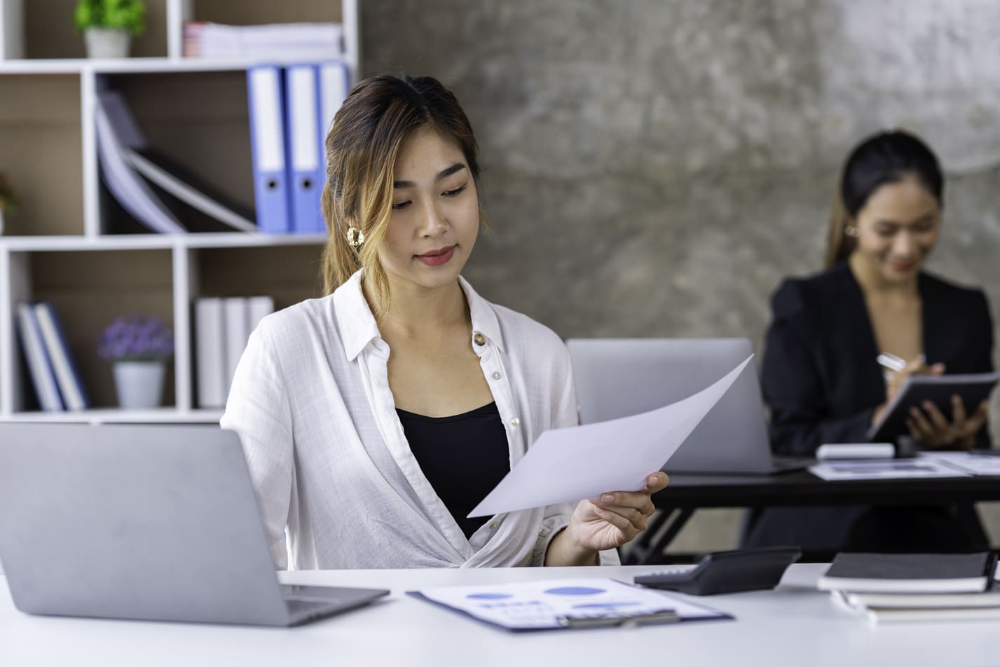 HR compliance specialist reviewing employment contracts and statutory social insurance records at an office workstation