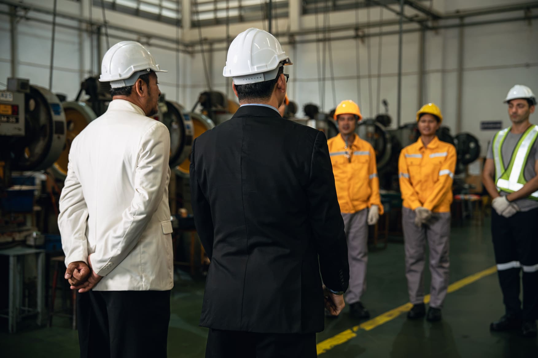 Factory supervisor conducting an onboarding briefing for seasonal workers on a plant floor
