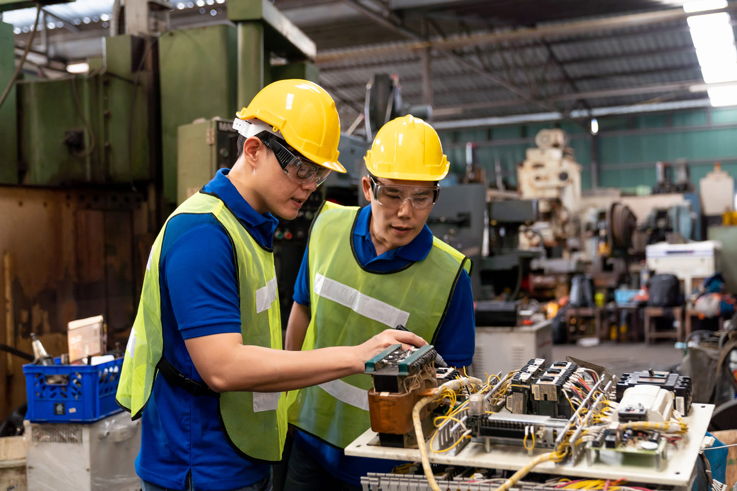 Veteran manufacturing employee guiding a team member on operational techniques during a shift