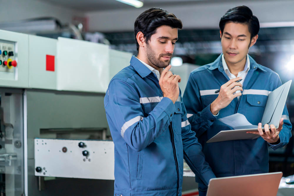 Senior technician guiding a new operator during hands-on training on a manufacturing floor