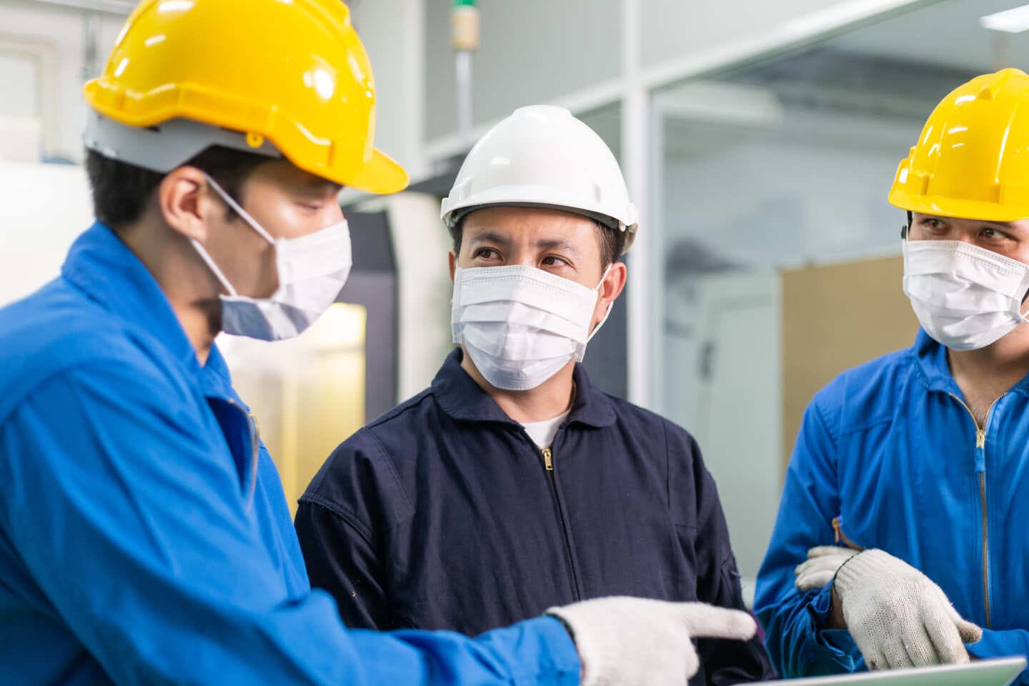 Factory operators working along an assembly line under supervisor guidance