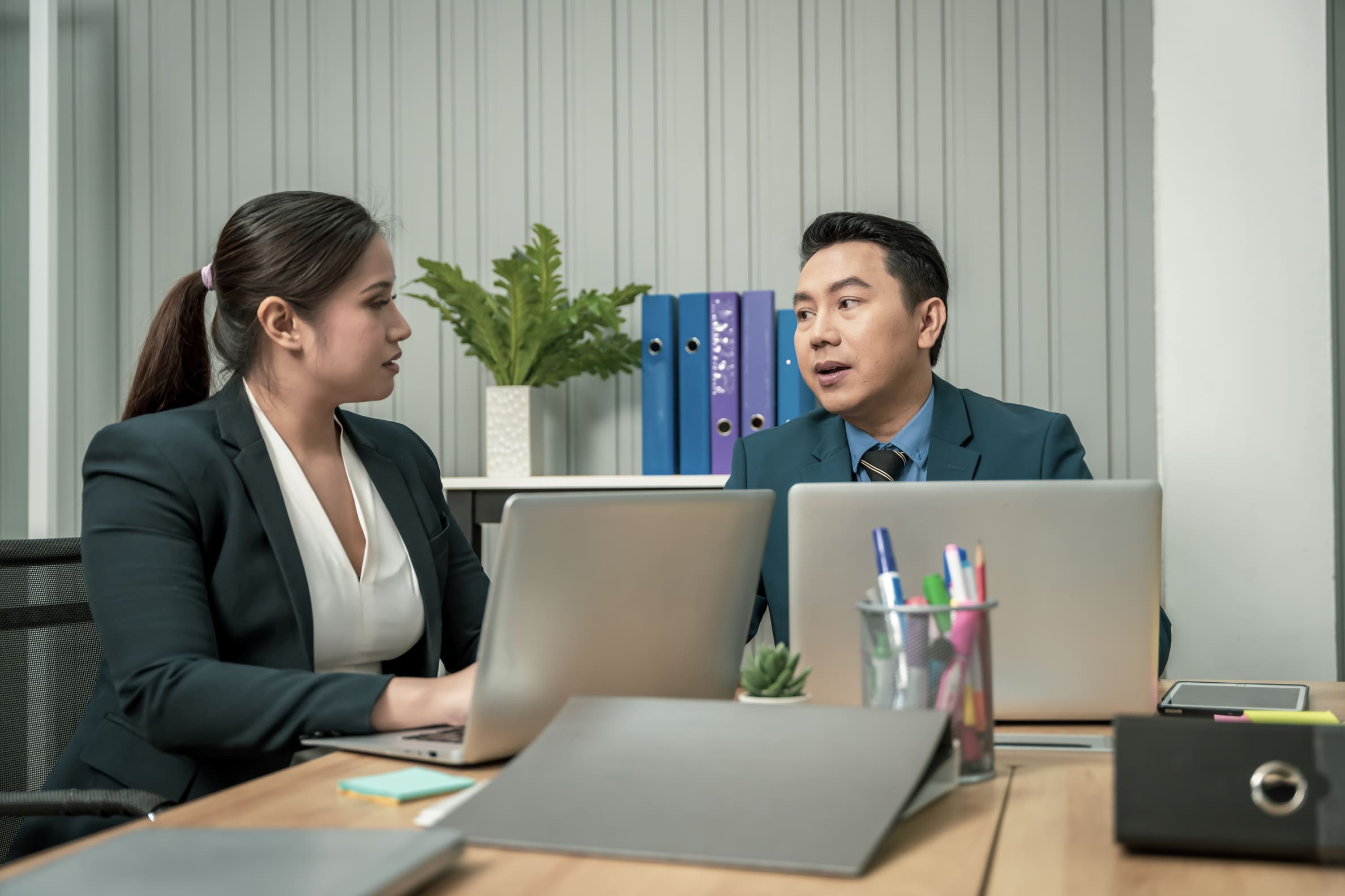 Manager having a one-on-one supportive conversation with an employee at an office desk