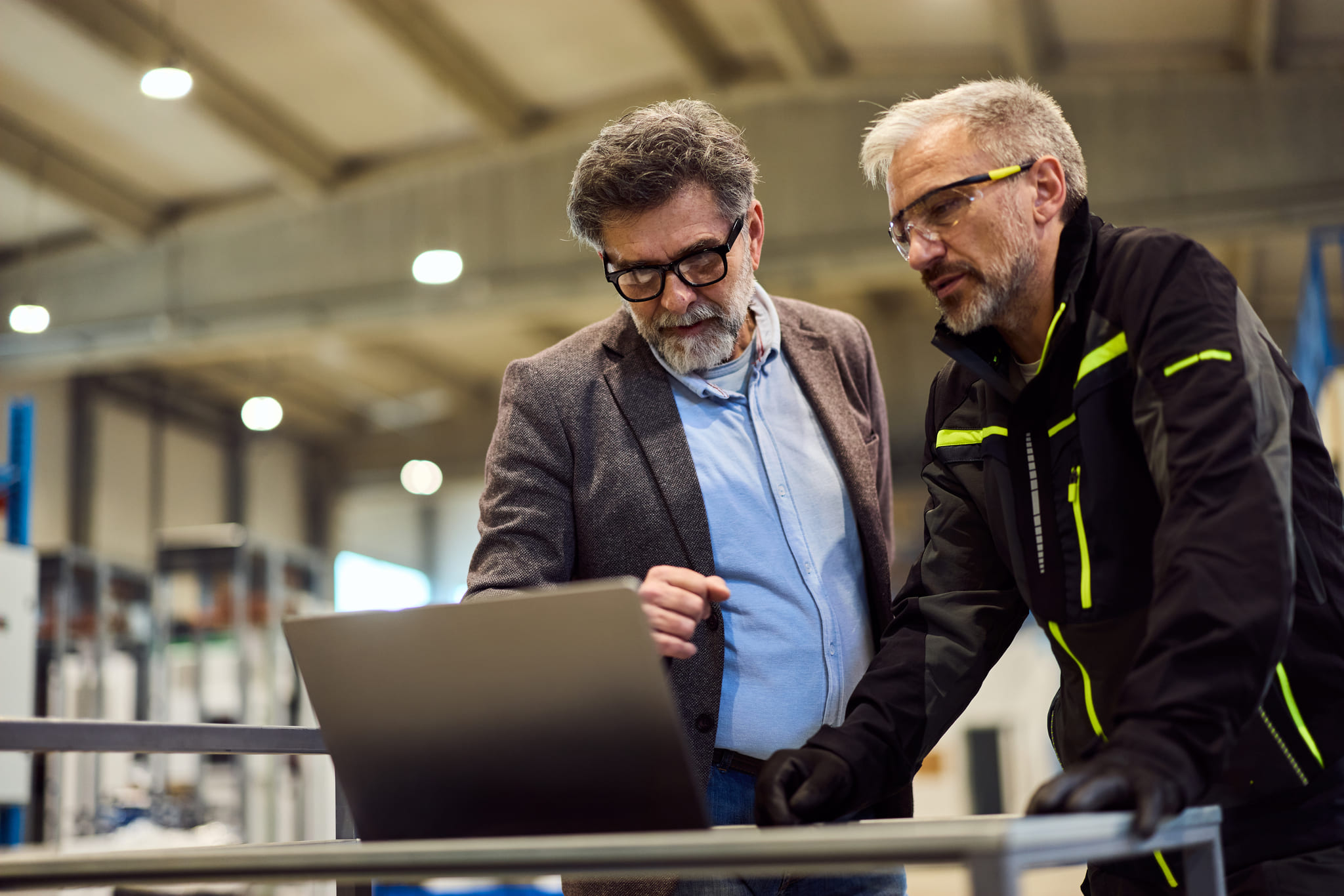 HR director and plant manager reviewing strategic workforce planning data on a laptop