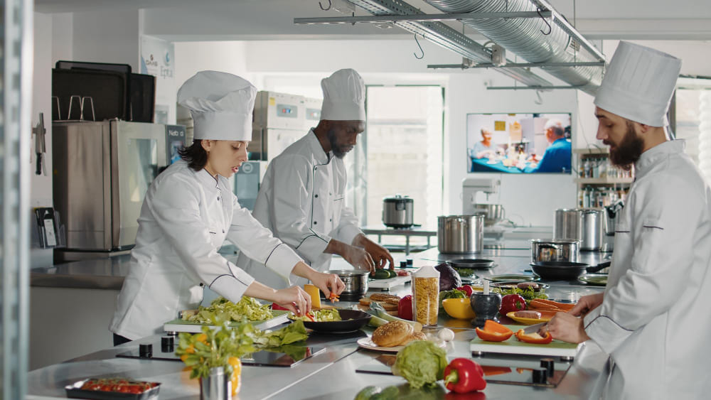 Executive chef and culinary staff preparing gourmet dishes in a high-end commercial restaurant kitchen.